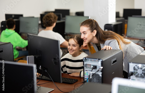 Принти на полотні Smiling female teacher talking to happy teenage girl student sitting at computer