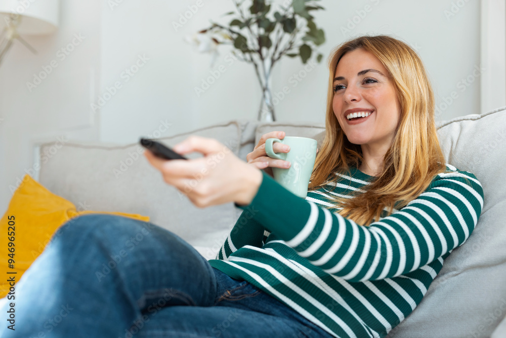 Pretty young woman turning on the tv while drink coffee on sofa at home Pretty young woman turning on the tv while drink coffee on sofa at home