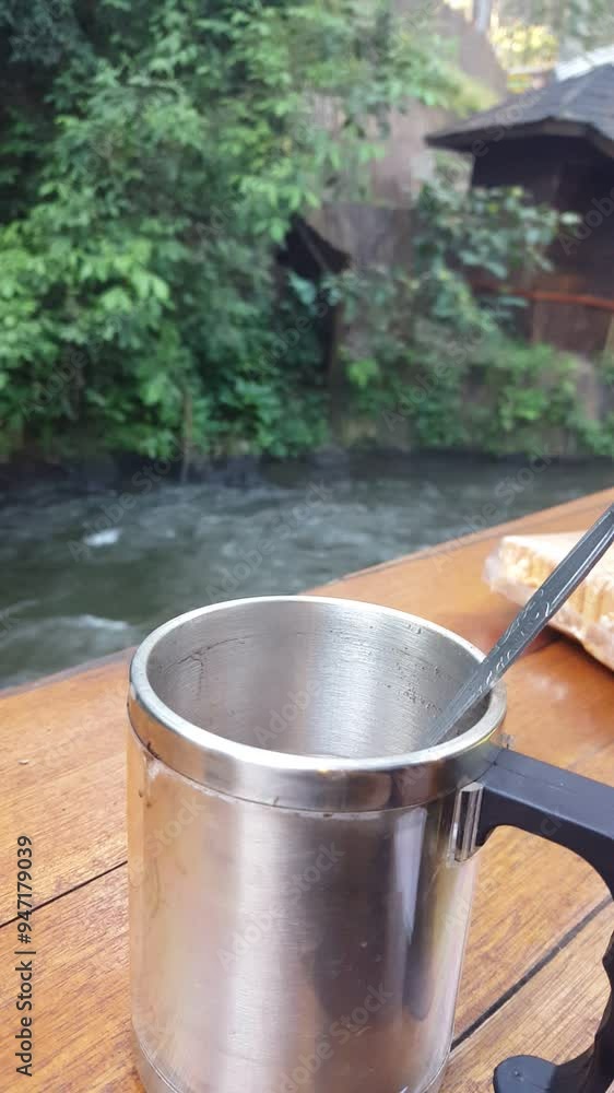 A hot drink amidst the cool natural atmosphere of a flowing river vertical video A hot drink amidst the cool natural atmosphere of a flowing river vertical video
