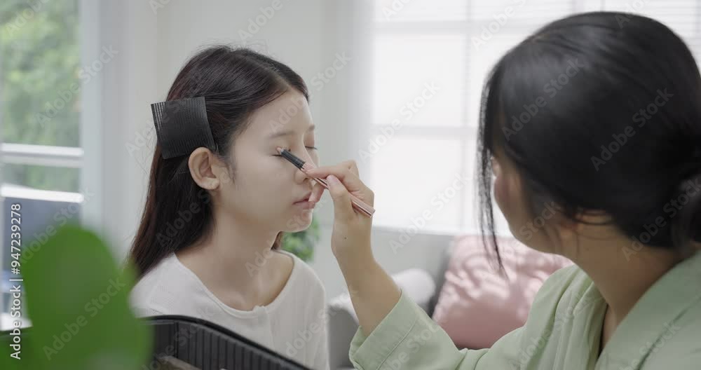 Young Asian model's make-up is done by a professional make-up artist. Makeup artist's face. Makeup artist applies powder to the model's face. Makeup artist in the process
