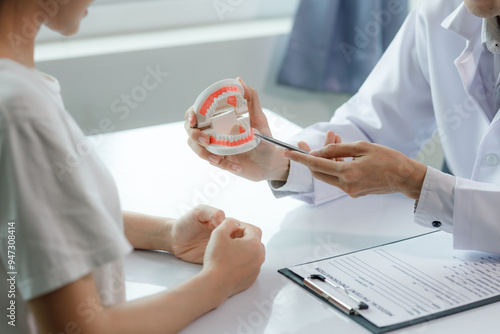 Obraz na płótnie A dentist advises a patient on dental care in a modern clinic, explaining oral hygiene and treatment options with tools or diagrams