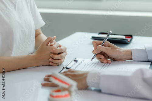 Billede på lærred A dentist advises a patient on dental care in a modern clinic, explaining oral hygiene and treatment options with tools or diagrams