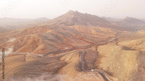 Aerial view of majestic mountains and a winding road in a vast desert valley, Mirador Astronomico de Sicasumbre, Fuerteventura, Canary Islands, Spain. photo