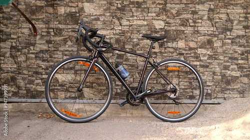 Racing bicycle leaning against stone wall. Road bike parked on sidewalk. Urban cycling and eco-friendly transportation concept.