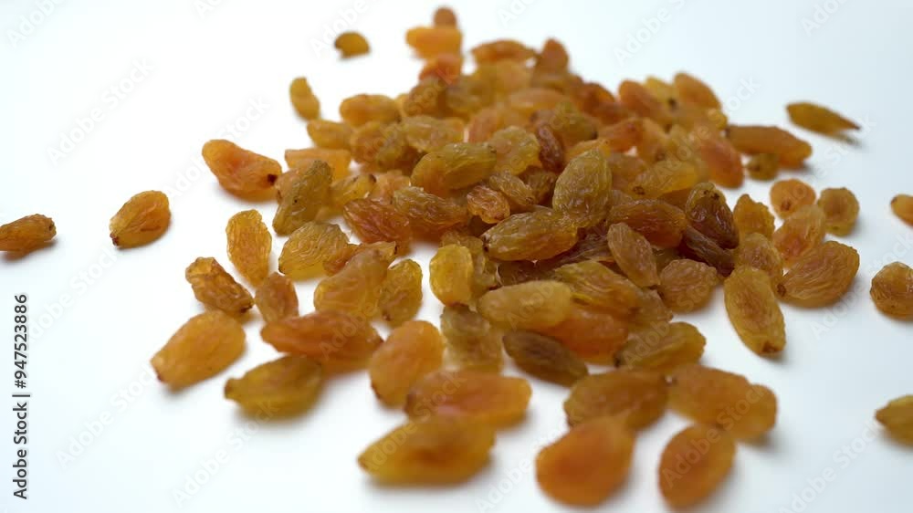 Scattered healthy raisins view on white table, close up of a plate of dried fruits and nuts Scattered healthy raisins view on white table, close up of a plate of dried fruits and nuts