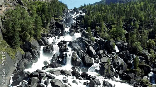 Aerial view of the cascading Uchar waterfall on the Chulcha River, flowing over rocks and pine forests. Beautiful wildlife in the Altai Mountains
