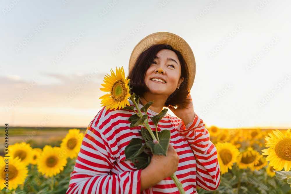 Smiling woman with sunflower wearing hat in field Smiling woman with sunflower wearing hat in field