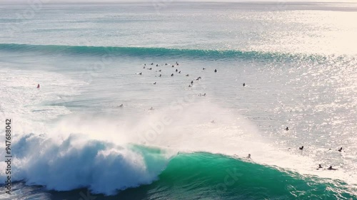 Perfect waves with surfers at Bali on Padang Padang beach. Drone view of surfing on ocean wave. 