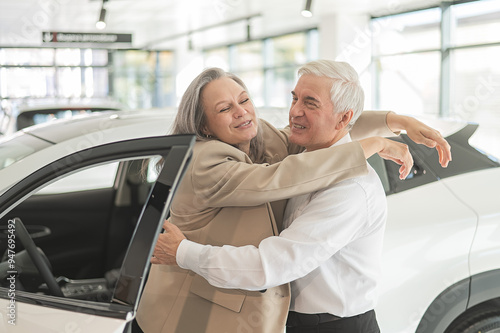 Mature Caucasian couple hugging. Elderly man and woman buying a new car.  photo