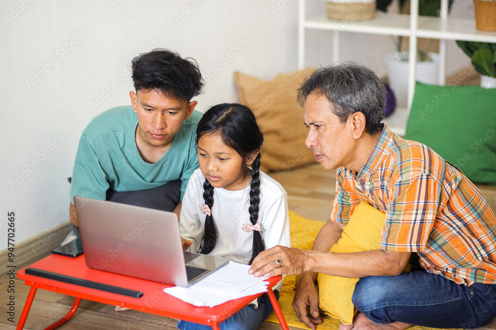Side View Of Concentration Asian Family Teaching Little Girl Using Laptop On Table While Sitting on The Flooor Side View Of Concentration Asian Family Teaching Little Girl Using Laptop On Table While Sitting on The Flooor