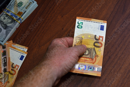 Male's Hand Holding 50 EURO Banknote on Brown Wooden Table. paper money, currency, cash, close-up. concepts of finance, payments, commerce, financial transactions, prosperity. photo