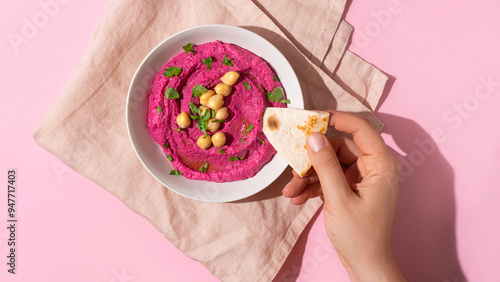 hand dipping pita bread in Beetroot hummus, top view
