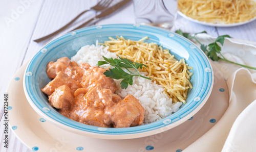 Chicken strogonoff in plate with rice and potato straw.
