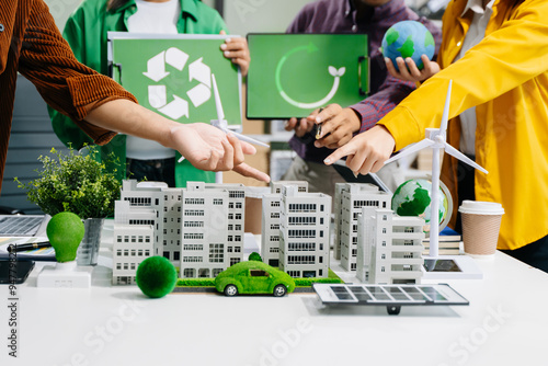 Group of diverse multiethnic businesspeople standing neare table looking at model of building from residential project. Green business company photo