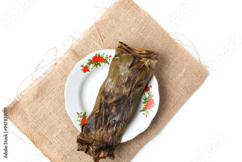 pepes ikan or fish wrapped in banana leaves with a mixture of traditional spices such as turmeric, onions, lemon grass, which are finely ground, and chopped tomatoes or chilies then steamed or grilled photo