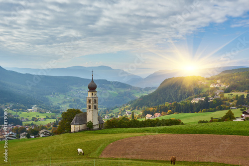 St. Valentin Kastelruth Village Church in the summer in the Dolomite Alps. Amazing landscape with small chapel on sunny meadow and Petz peak at Kastelruth commune. Dolomites, Italy photo