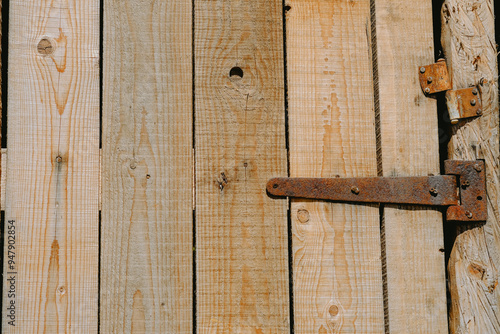 Close-up of rustic wooden door with rusted hinge showcasing natural wood grain and texture