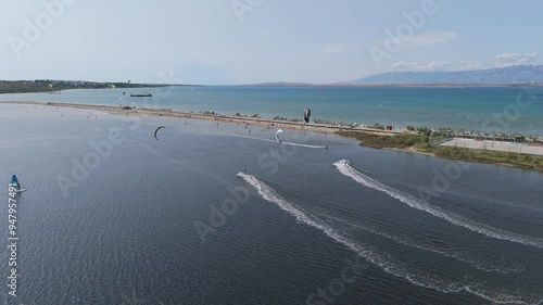 Aerial Shot of Kite Surfers From a Drone in the Zdrijac Beach City of Nin, Croatia. Trouists Relaxing on Sandy Zdrijac Beach and in Adriatic Sea With Mountain Range of Dinaric Alps in the Background photo