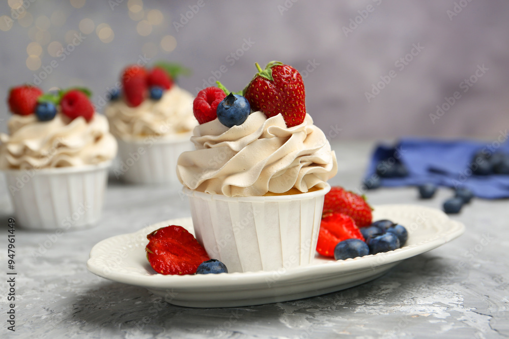 Tasty cupcakes with different berries on light grey table, closeup Tasty cupcakes with different berries on light grey table, closeup