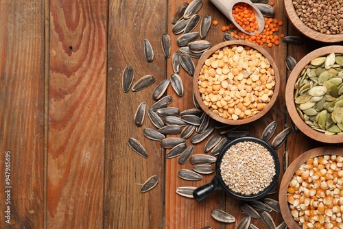 Different types of cereals, legumes and seeds on wooden table, flat lay. Space for text