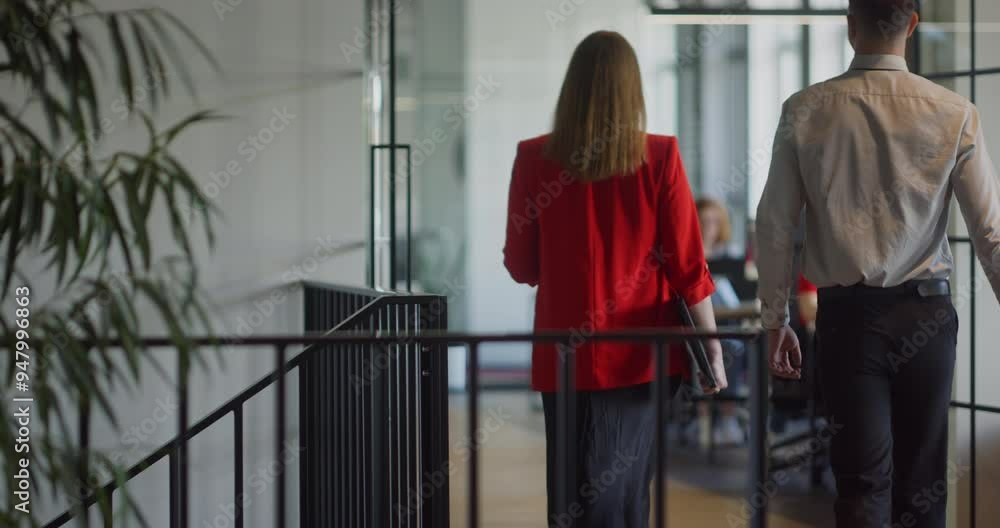 Two young business colleagues walking through a modern startup office and engaging in a dynamic discussion about various business challenges. Two young business colleagues walking through a modern startup office and engaging in a dynamic discussion about various business challenges.