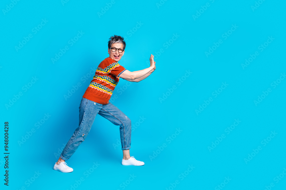 Full size photo of nice aged woman push empty space wear t-shirt isolated on blue color background Full size photo of nice aged woman push empty space wear t-shirt isolated on blue color background
