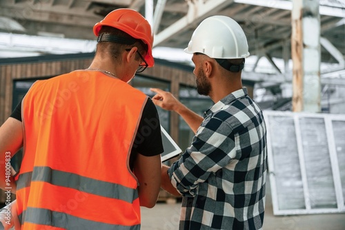 Two workers are in the industrial wooden warehouse