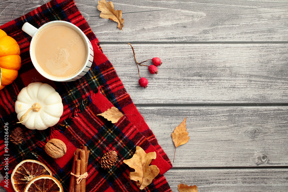 Fototapeta premium Cozy home desk table with red plaid, coffee cup, pumpkins, dry leaves, red berries. Autumn, fall concept. Hygge, nordic style. Flat lay, top view.