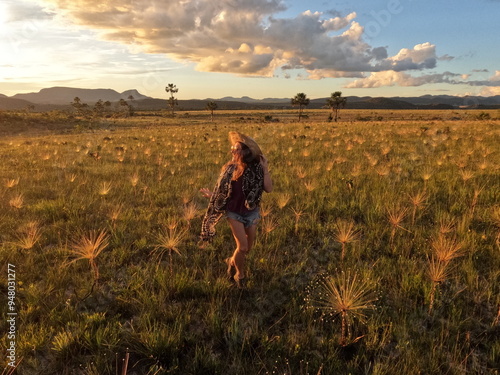 mulher caminhando em campo com palipalan (conhecidos como "chuveirinhos") na chapada dos veadeiros, goiás