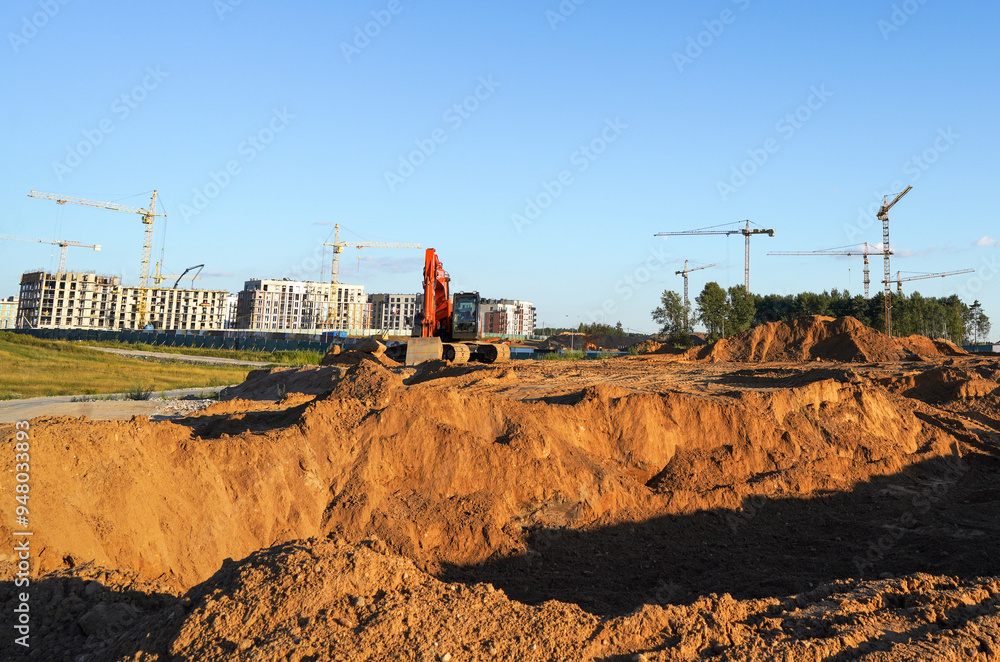 Excavator digging a foundation. Building construction. Tower Cranes on Residential Buildings construction. Excavator on groundwork on Construction site. Heavy construction equipment on excavation. Excavator digging a foundation. Building construction. Tower Cranes on Residential Buildings construction. Excavator on groundwork on Construction site. Heavy construction equipment on excavation.