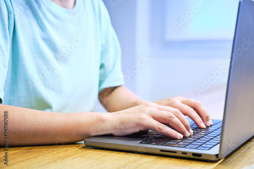 Woman's hands typing on a laptop on a brown wooden table