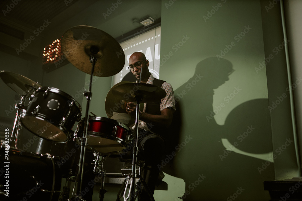 Fototapeta premium Low angle view of young Black man setting cymbal while assembling drum kit in studio, copy space