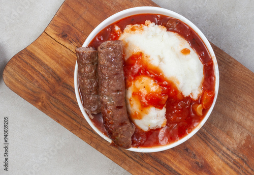 Slika na platnu Traditional South African Pap, wors and Sheba sauce flat lay with wooden board