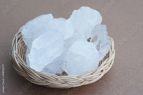 Foto Crystal clear alum stones or Potassium alum on basket isolated on brown background