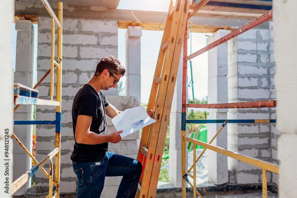 Man architect engineer checking house under construction comparing with blueprint plan on paper. Gas block Man architect engineer checking house under construction comparing with blueprint plan on paper. Gas block