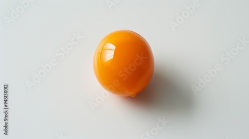 A pristine, single orange egg yolk isolated on a bright white backdrop, highlighting its vibrant hue and smooth surface.