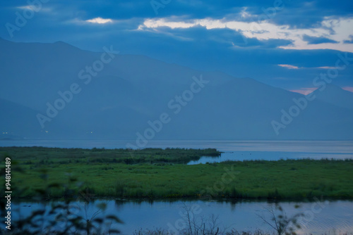 Tranquil lake with misty mountains at dawn