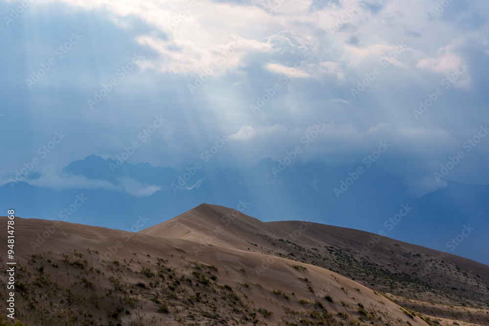 Sunbeams illuminating desert hills under cloudy sky Sunbeams illuminating desert hills under cloudy sky