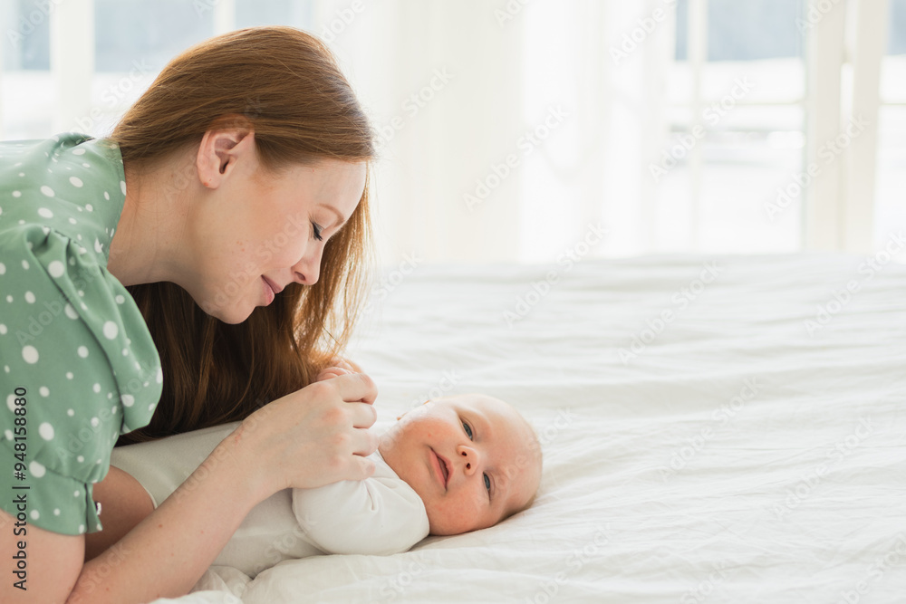 Happy family at home. Mother playing with little toddler child on bed. Mom baby relax playing having fun together. Mother looks at baby with love care. Mom of breast feeding baby rest in living room Happy family at home. Mother playing with little toddler child on bed. Mom baby relax playing having fun together. Mother looks at baby with love care. Mom of breast feeding baby rest in living room