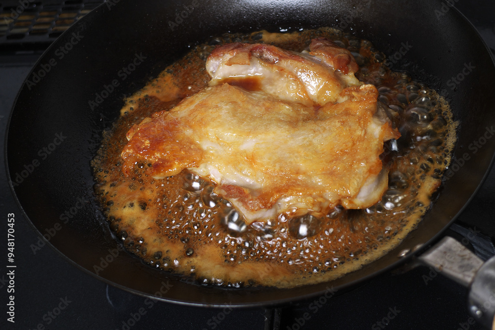 フライパンの上で調理中の日本の鶏モモ肉の照り焼き フライパンの上で調理中の日本の鶏モモ肉の照り焼き
