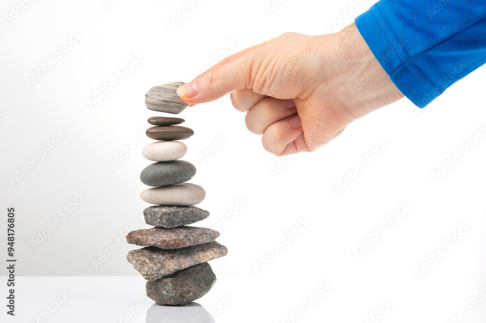 hand builds a pyramid from stacked stones on a white background. stabilization and balance in life hand builds a pyramid from stacked stones on a white background. stabilization and balance in life
