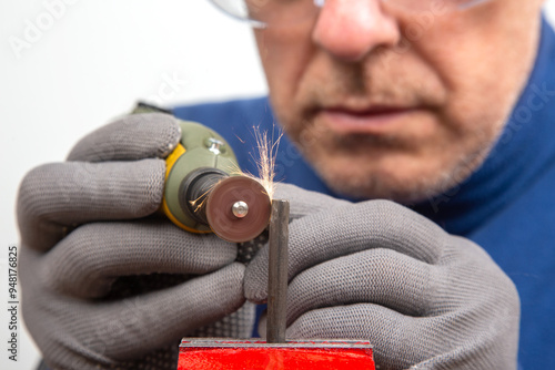 experienced locksmith in protective gloves carefully processing metal with an engraving drill, focusing on precision and craftsmanship. industrial metalworking in a professional mechanic's workshop