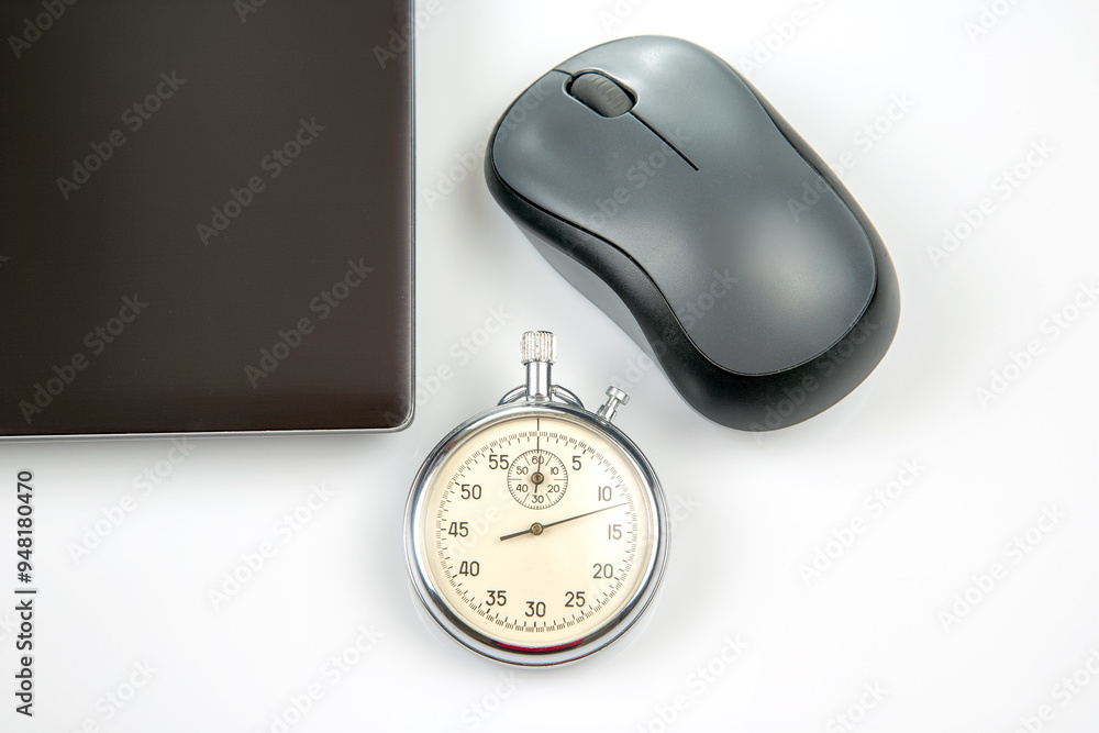 mechanical stopwatch on a background of a computer mouse and laptop on ...