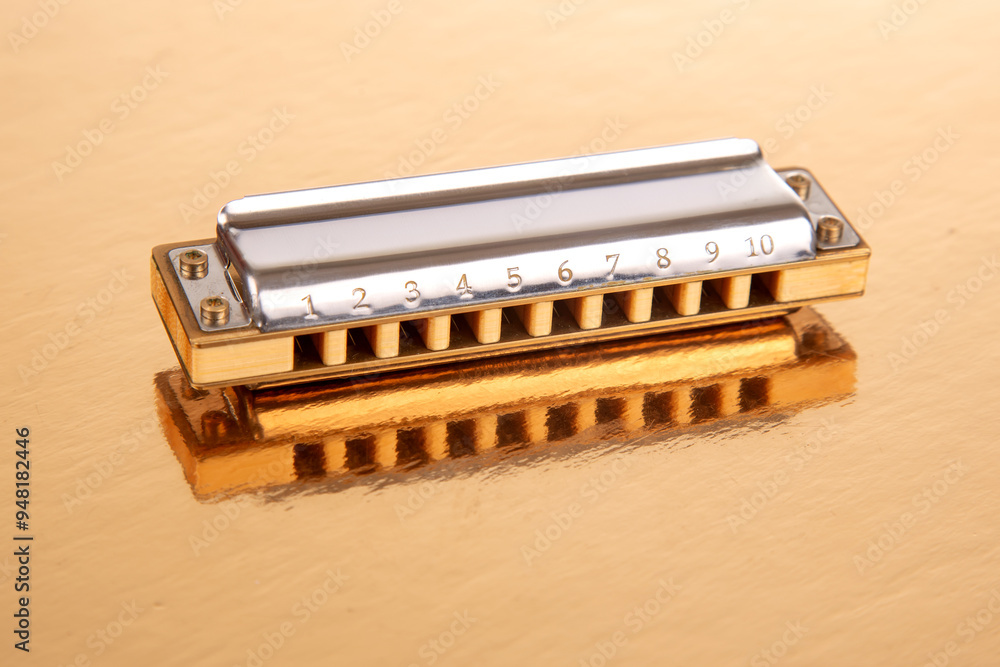 The harmonica lies on a mirrored surface. Classical musical wind instrument.
