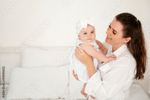 Fotografie mom and baby hug and kiss at home on the bed in the bedroom, parental love and c