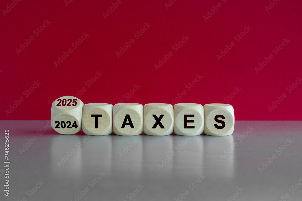 2025 taxes new year symbol. Turned a wooden cube and changes words Taxes 2024 to Taxes 2025. Beautiful grey table pink background. Business 2025 taxes new year concept.