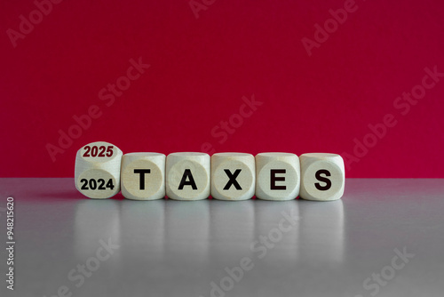 Obraz na płótnie 2025 taxes new year symbol. Turned a wooden cube and changes words Taxes 2024 to Taxes 2025. Beautiful grey table pink background. Business 2025 taxes new year concept. w salonie
