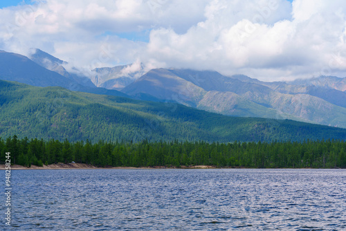 Calm lake with misty mountains and tree-lined shore