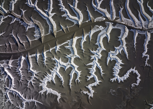 Aerial and top angle view of tidal channel of black mud flat at low tide with white ice and snow near Hwangsando Island, Ganghwa-gun, South Korea  photo