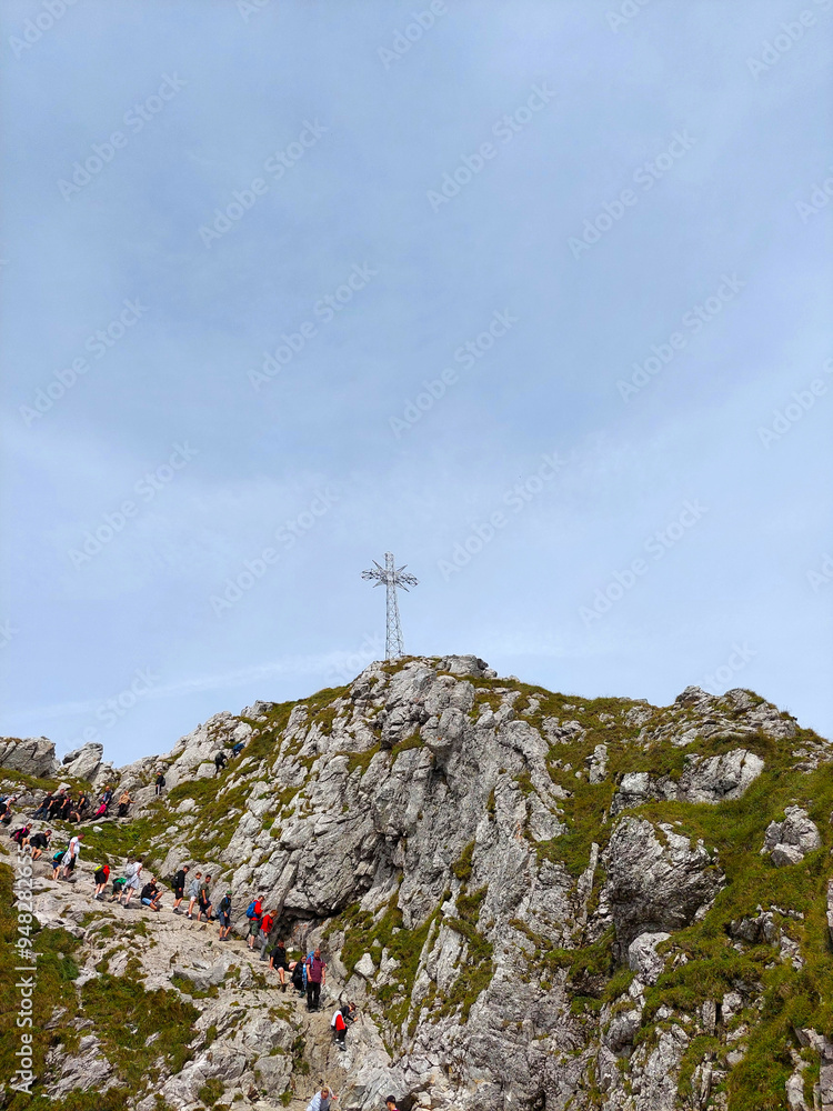 Fototapeta premium Tourists are enjoying a challenging climb on a rocky mountain path to reach the summit of giewont mountain in poland